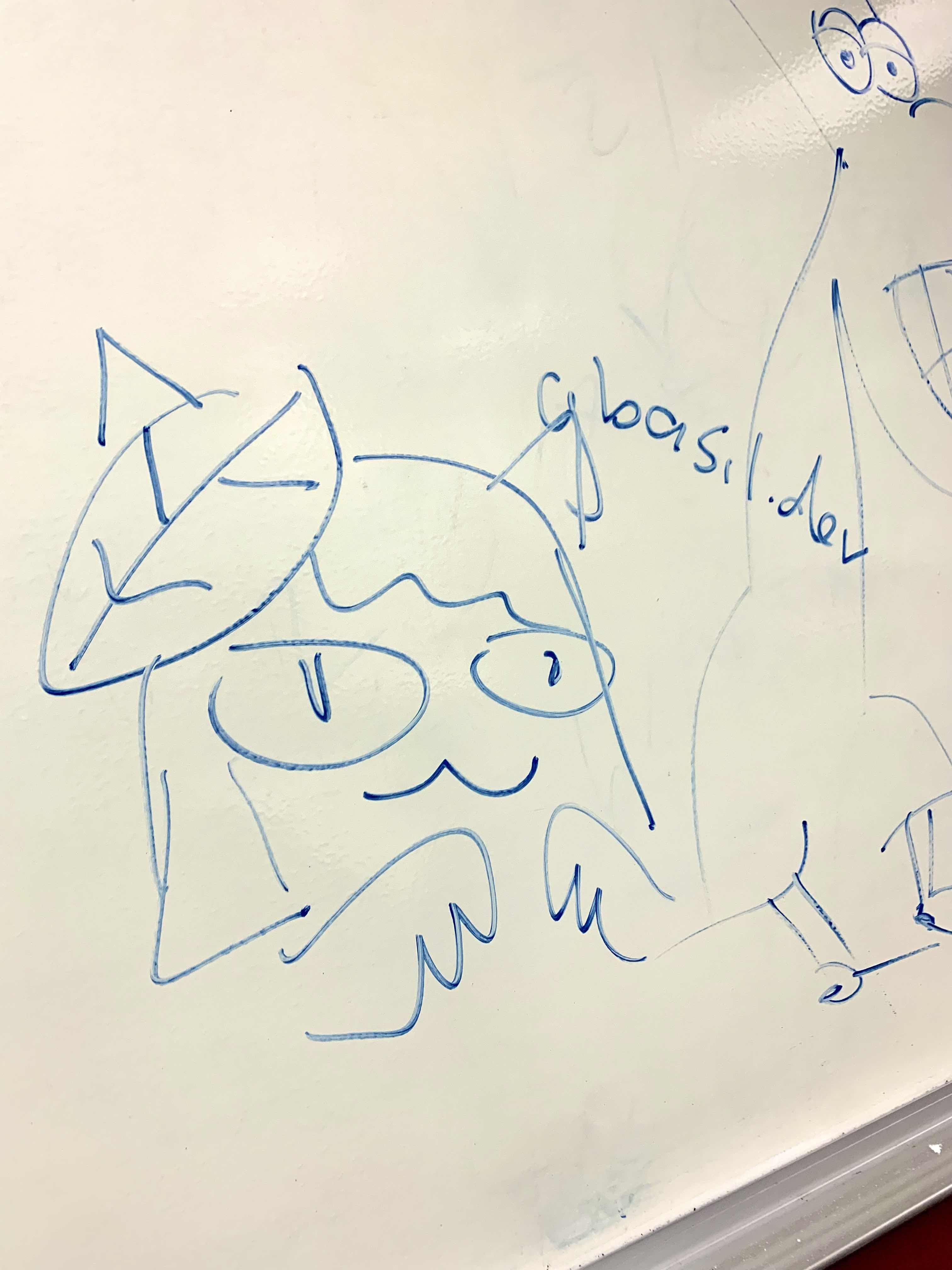 A photo of a drawing on a whiteboard of the head and hands of a catgirl with a large basil leaf on her head. The drawing is made with a blue marker.